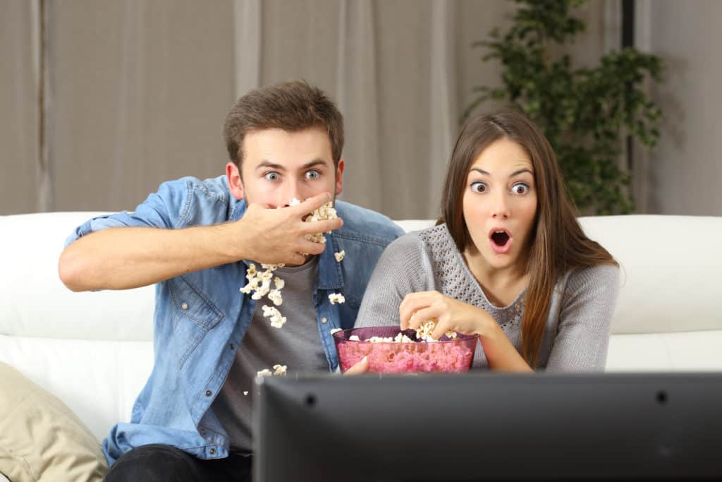 young couple watching television and eating popcorn